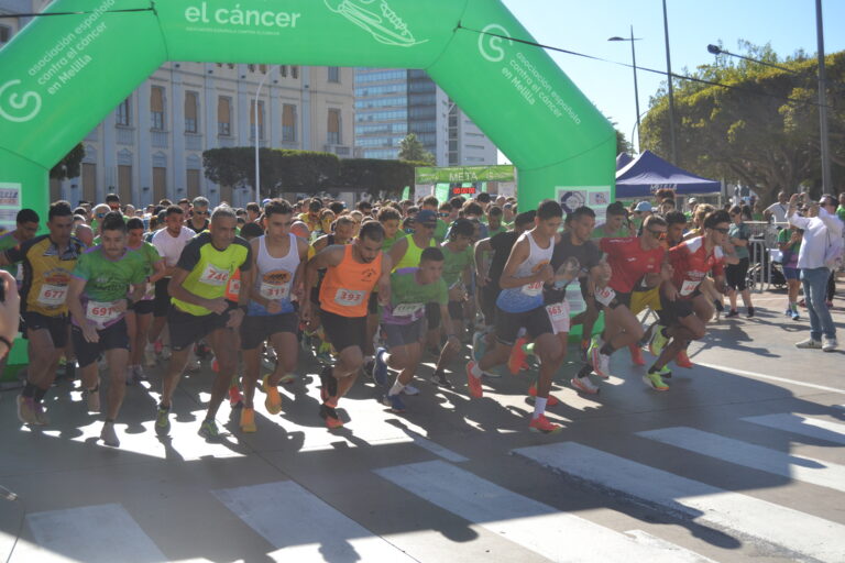 Corredores toman la salida bajo un arco verde de la Asociación Española Contra el Cáncer.