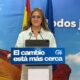 Woman at a podium delivering a speech, with a blue banner reading 'El cambio está más cerca' and flags in the background.