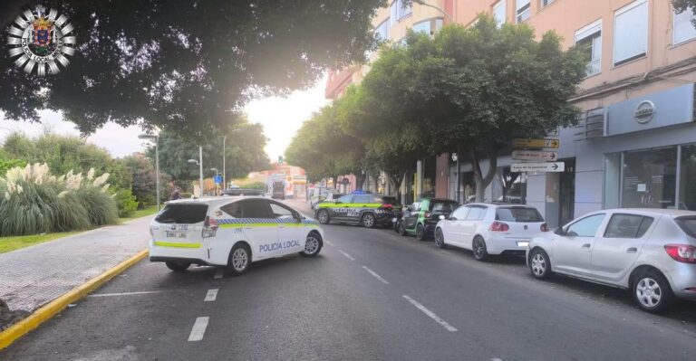 Dos vehículos de la Policía Local estacionados en una calle urbana arbolada.