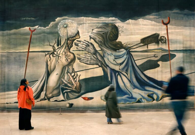 Visitantes contemplan una gran pintura surrealista en una sala de exposición.